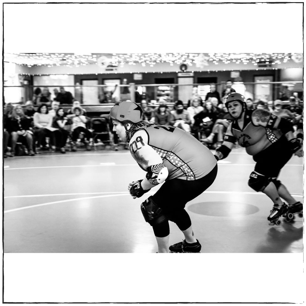 Wendy and Jumpy Playing roller derby maine Jammer coming around the apex with blocker in pursuit 