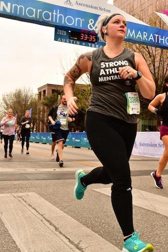 Kat Uhstrauphik running in the Austin Marathon wearing her Strong Athletic Mentally Ill tank top 