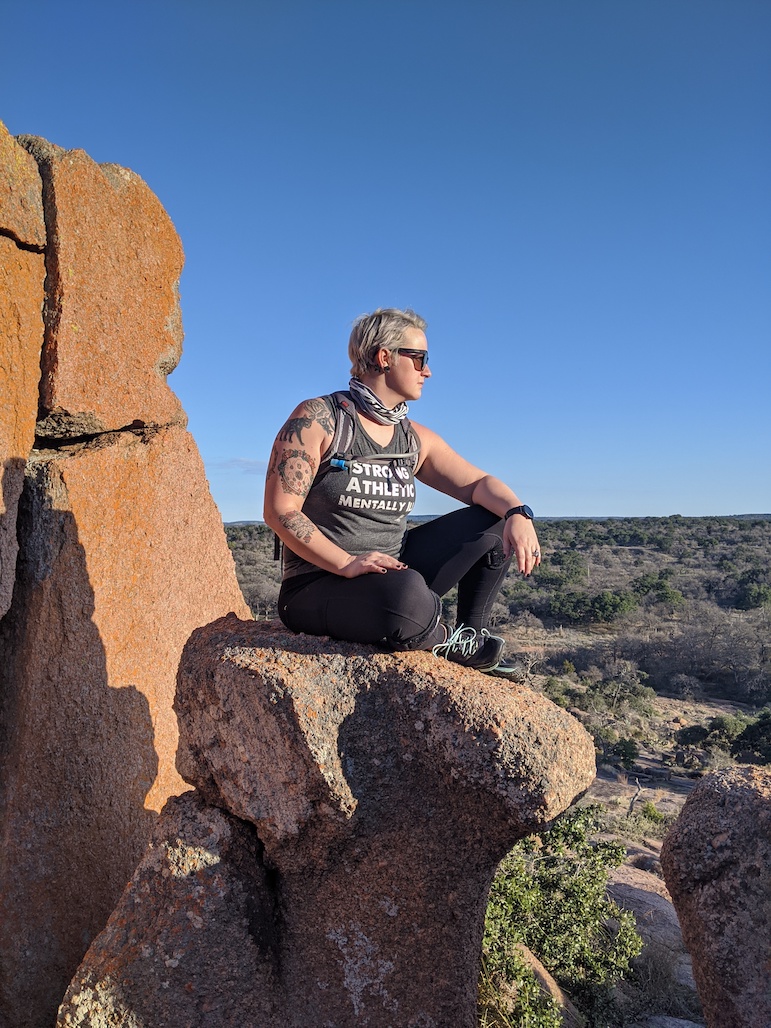 Kat Uhstrauphik at Enchanted Rock in Texas wearing her Strong Athletic Mentally Ill tank top 